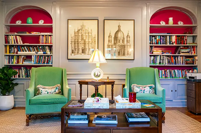 Two comfortable looking green wingback chairs sit in front of built-in bookcases